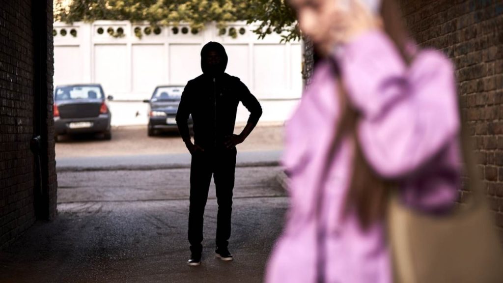 Ilustračná fotografia: Žena kráča osamote ulicou, zatiaľ čo v pozadí stojí neznámy muž. Pocit, že nás niekto sleduje, môže vzniknúť aj na základe nenápadných podnetov, ktoré mozog vyhodnotí ako možnú prítomnosť iného človeka. Niekedy však môže ísť iba o mylný dojem. Foto: Shakirov Albert / Shutterstock