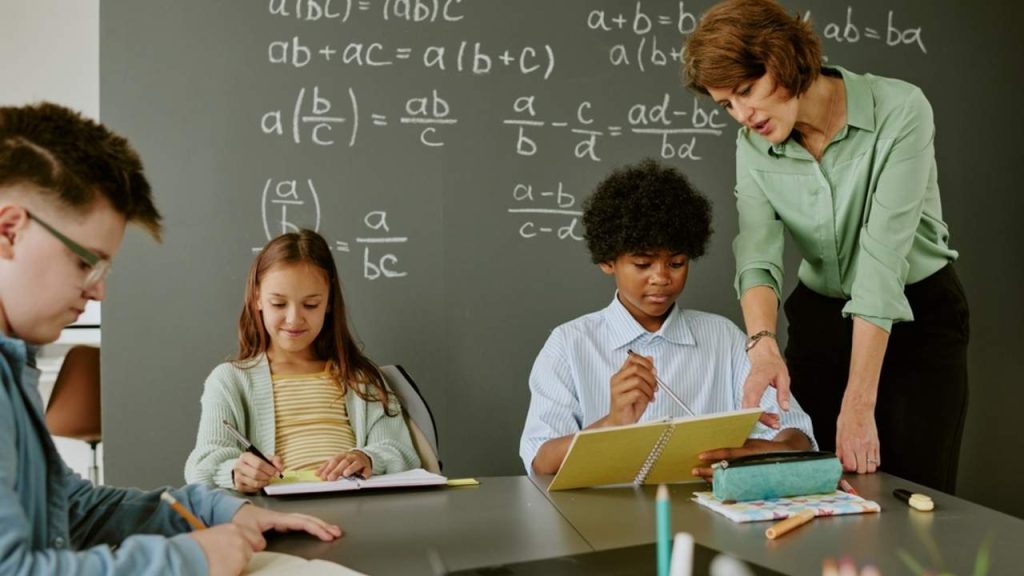 Ilustračná fotografia: Učiteľka pomáha žiakovi pri riešení úloh počas vyučovania matematiky. Nový vedecký výskum ukazuje, že matematické výsledky súvisia nielen so schopnosťou počítať, ale aj s logickým uvažovaním, porozumením jazyku a ďalšími poznávacími schopnosťami. Foto: AnnaStills / Shutterstock